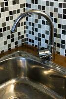 pulito Lavello con scrosciante acqua nel il cucina, metallo rubinetto e Lavello nel un vecchio casa interno. foto