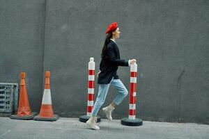 moda donna in esecuzione giù il strada nel davanti di il città turista nel elegante Abiti con rosso labbra e rosso berretto, viaggiare, cinematico colore, retrò Vintage ▾ stile, in ritardo per opera, correre. foto