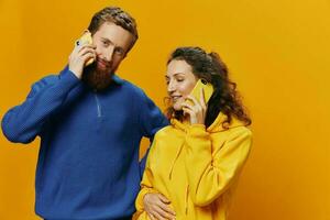 uomo e donna coppia sorridente allegramente con Telefono nel mano sociale media visualizzazione fotografie e video, su giallo sfondo, simboli segni e mano gesti, famiglia liberi professionisti.