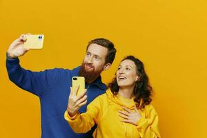 uomo e donna coppia sorridente allegramente con Telefono nel mano sociale media visualizzazione fotografie e video, su giallo sfondo, simboli segni e mano gesti, famiglia liberi professionisti.