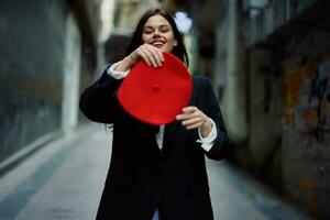 moda donna Sorridi con denti e divertimento turista nel elegante Abiti nel giacca e rosso berretto a piedi giù stretto città strada volante capelli, viaggiare, francese stile, cinematico colore, retrò Vintage ▾ stile. foto