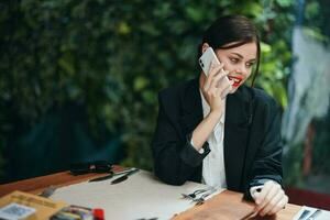 moda donna blogger turista nel un' bar con un' Telefono nel sua mani parlando su il Telefono, mobile comunicazioni e il Internet su un' primavera viaggio, video chiamata, libero professionista opera in linea, Sorridi, comunicazione foto