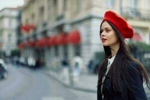 moda donna ritratto bellezza in piedi su il strada nel davanti di il città nel elegante Abiti con rosso labbra e rosso berretto, viaggiare, cinematico colore, retrò Vintage ▾ stile, urbano moda stile di vita. foto