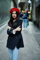 moda donna ritratto a piedi turista nel elegante Abiti con rosso labbra a piedi giù stretto città strada, viaggiare, cinematico colore, retrò Vintage ▾ stile, drammatico Guarda senza Sorridi tristezza. foto