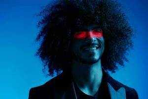 moda ritratto di un' uomo con Riccio capelli su un' blu sfondo con un' rosso banda di luce, multicolore luce, di tendenza, moderno concetto. foto