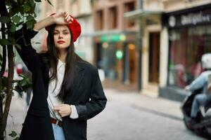 donna modello sta su il strada nel il città nel un' giacca e rosso berretto, cinematico francese moda stile vestiario, viaggio per Istanbul foto