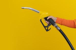 donna tenere l'ugello del carburante su sfondo giallo