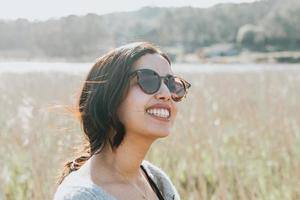 donna che utilizza occhiali da sole sorridendo alla telecamera mentre si trovava nel cortile del paese foto