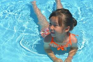 contento poco ragazza nuoto piscina su un' caldo estate giorno. bambini imparare per nuotare. bambino acqua giocattoli. bambini giocare nel tropicale resort. famiglia spiaggia vacanza. foto