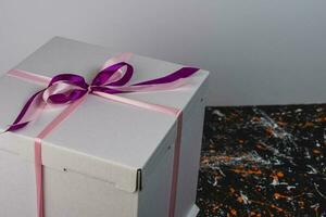 bianca regalo scatola legato con un' rosso nastro su un' macchiato colorato sfondo foto