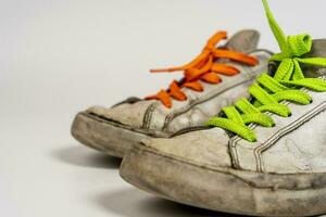 logoro vecchio strappato bianca scarpe da ginnastica con colorato lacci su un' bianca sfondo foto