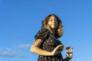 attraente ragazza con lungo capelli nel alla moda Marrone vestito contro cielo foto