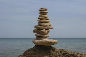 bilanciamento piramide di pietre su una grande pietra in riva al mare foto