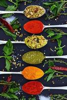 colorate varie erbe e spezie per cucinare su sfondo scuro foto