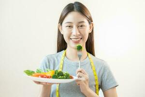 dieta, dieta asiatico giovane donna o ragazza uso forchetta a broccoli su mescolare la verdura, verde insalata ciotola, mangiare cibo è Basso Grasso bene Salute. dietologo femmina, peso perdita per salutare persona. foto