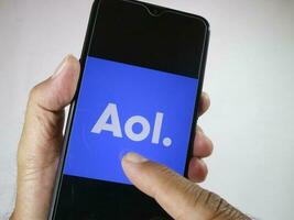 Giacarta, Indonesia, 2023. mano Tenere mobile Telefono con dito toccare il aol logo su schermo. foto