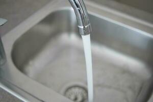 acqua scrosciante a partire dal un' rubinetto rubinetto lento movimento foto