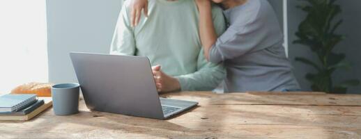 abbracciato maturo coppia fare surf il Internet su il computer portatile a casa foto