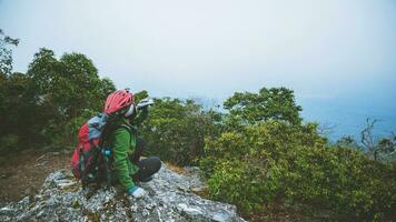 natura di viaggio donna asiatica. viaggiare rilassati. sedersi e guardare i paesaggi naturali sulla scogliera. vacanza in montagna. foto