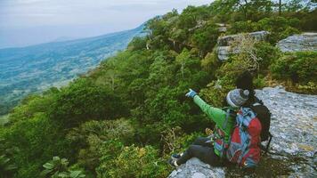 asiatico amante donne e uomini viaggio natura. viaggio relax. paesaggi su il scogliera. coppie viaggio nel il montagne. ammirare il atmosfera paesaggio su il montagna. viaggio Tailandia. foto