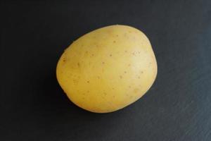 patata fresca cruda sul tavolo di pietra nera foto