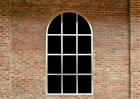 curva finestra con nero bicchiere su mattone parete foto