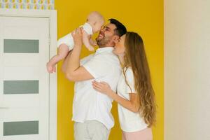 contento genitori hold loro bambino figlio nel loro braccia a il superiore, Guarda a lui e Sorridi foto