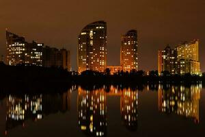 notte città con riflessione di case nel il fiume foto