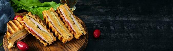 club Sandwich con prosciutto, formaggio, pomodoro e insalata. grigliato Sandwich con secco pomodori pane foto