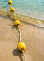 boa galleggiante e corda che dividono l'area sulla spiaggia foto