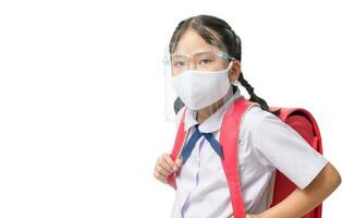asiatico ragazza alunno indossare viso scudo e maschera trasporta scuola Borsa isolato foto