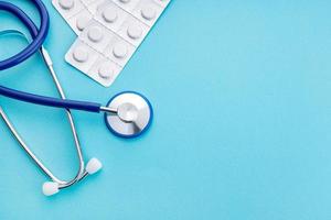 stetoscopio e pillole di medicina su sfondo blu concetto di assistenza sanitaria o farmacia sfondo spazio copia vista dall'alto