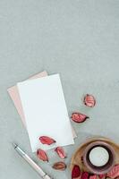 vuoto rosa e bianca carta con candela e petali, su grigio sfondo. foto