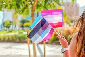 Genere queer. donna onda LGBTQ gay orgoglio arcobaleno bandiere a un' orgoglio evento. selettivo messa a fuoco. foto