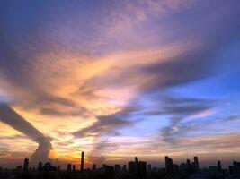 tramonto nel il sera con drammatico forma e colore di nuvole e cielo con silhouette di paesaggio urbano, edificio orizzonte, paesaggio nuvoloso, natura sfondo foto