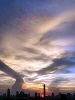 verticale Immagine, tramonto nel il sera con drammatico forma e colore di nuvole e cielo con silhouette di paesaggio urbano, edificio orizzonte, natura sfondo foto