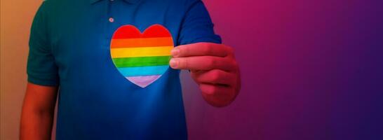 uomo mani hold cuore nel il colori di arcobaleno. lgbt diritti, orgoglio mese, tolleranza e amore concetto. foto