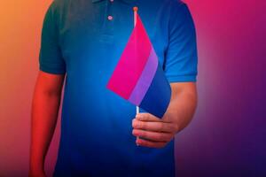 mano Tenere bandiera nel bisessuale orgoglio colori. foto
