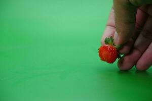 mano Tenere un' Bitten fragola isolato su verde sfondo. foto