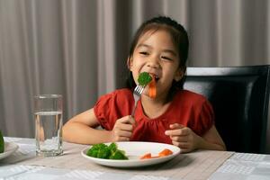 asiatico poco ragazza mangiare salutare verdure con assaporare. foto