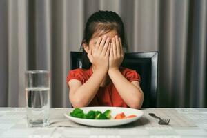 poco carino ragazzo ragazza rifiuto per mangiare salutare verdure. bambini fare non piace per mangiare verdure. foto