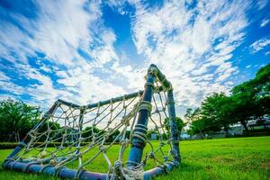 corda netto obiettivo, mini calcio campo con verde erba semplice, vecchio stile miniatura zanzara reti intrecciata con cannuccia ingombrare su il parco cielo e bianca nuvole sfondo, selettivo messa a fuoco, morbido messa a fuoco. foto