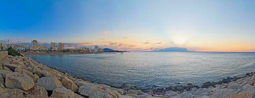 panoramico Immagine di il crescente sole al di sopra di il spiaggia di il spagnolo cittadina di vinaros foto