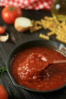 pomodoro salsa con di legno cucchiaio nel getto ferro tegame padella foto