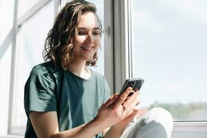 collegato nel solitudine, un' giovane donna abbraccia tecnologia per comunicazione e connessione mentre praticante sociale distanziamento a casa foto