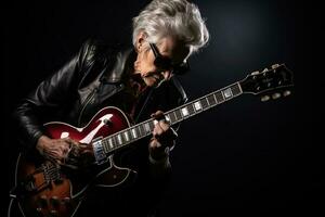 ritratto di un' freddo di moda vecchio donna giocando un' chitarra su nero studio sfondo. ai generato foto