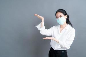 la donna asiatica che indossa una maschera medica protegge la polvere del filtro e il covid 19 con la presentazione a mano
