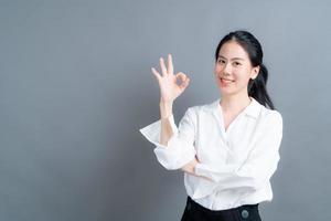 giovane donna asiatica che sorride e che mostra il segno giusto?