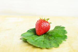 singola fragola con una foglia verde da vicino foto