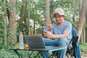 asiatico uomo seduta nel il giardino sotto il albero foto